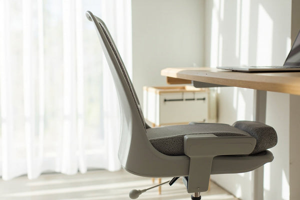 setup télétravail minimaliste avec support ordinateur, coussin ergonomique et correcteur posture